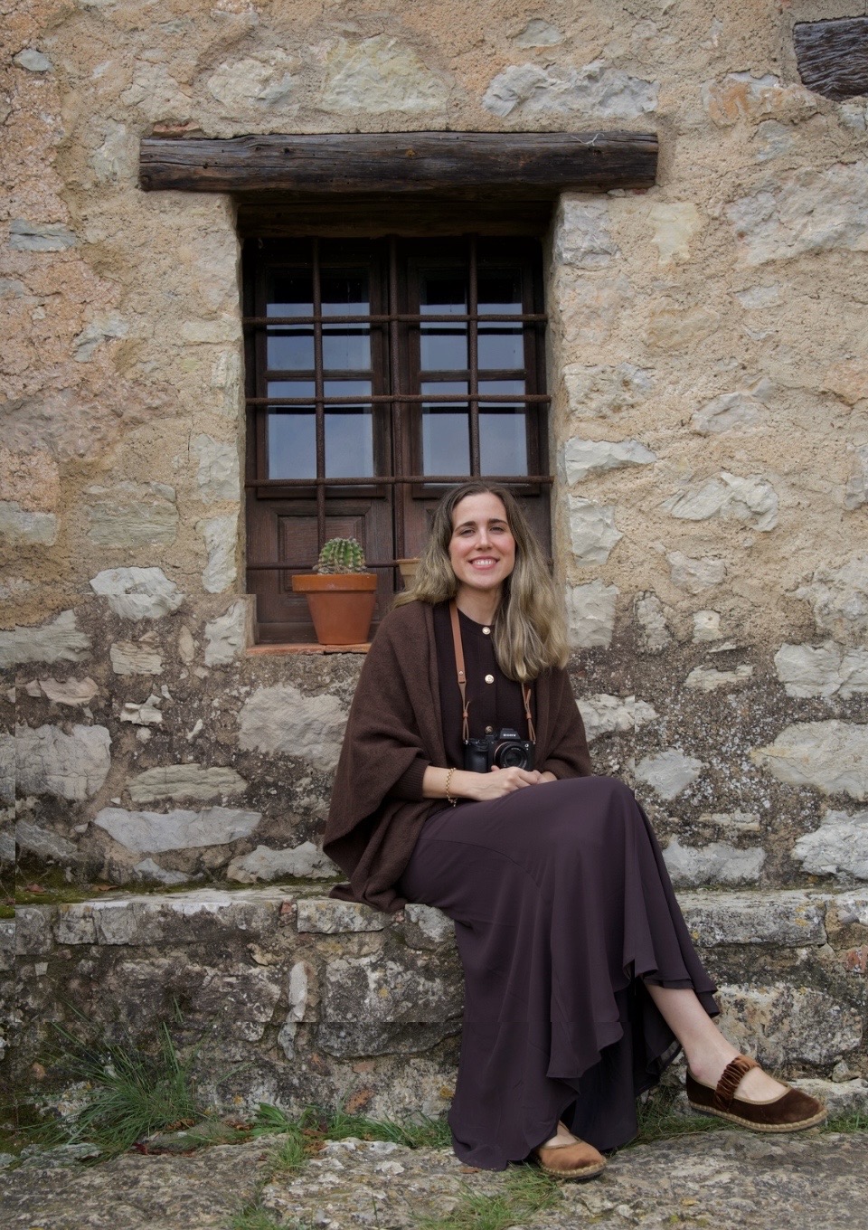 Inés Hernández sentada frente a una ventana de piedra con la cámara en las manos